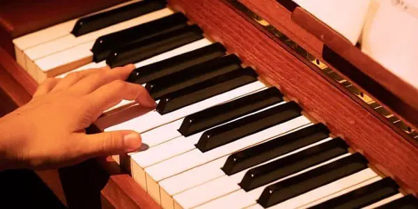 Hand playing a chord inversion on a piano.