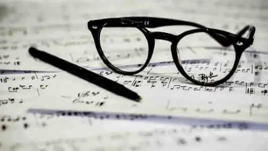 Eyeglasses an pencil on sheet music.